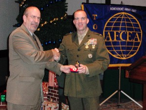 In November, Col. Kent Simon, USMC (r), commander of the Defense Information Systems Agency-Pacific, receives a token of appreciation from Lance Gatling, chapter president.